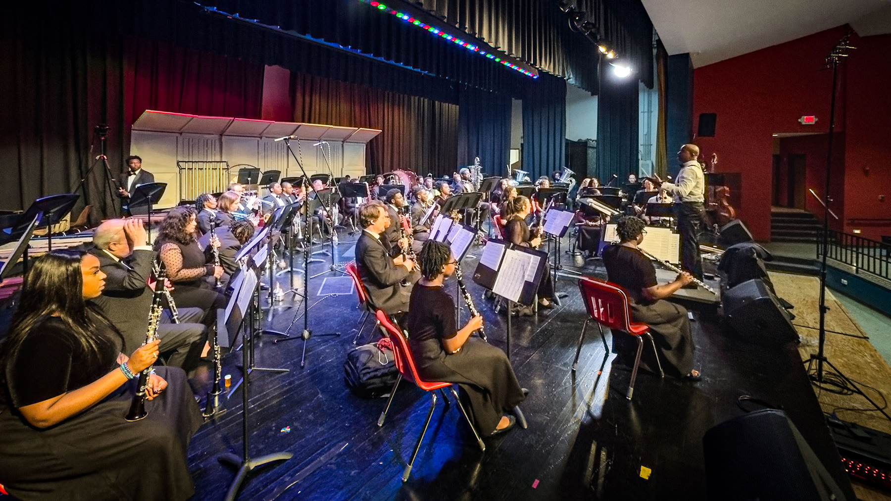 The VSU Wind Symphony performing onstage beneath the microphone array used for its annual recording